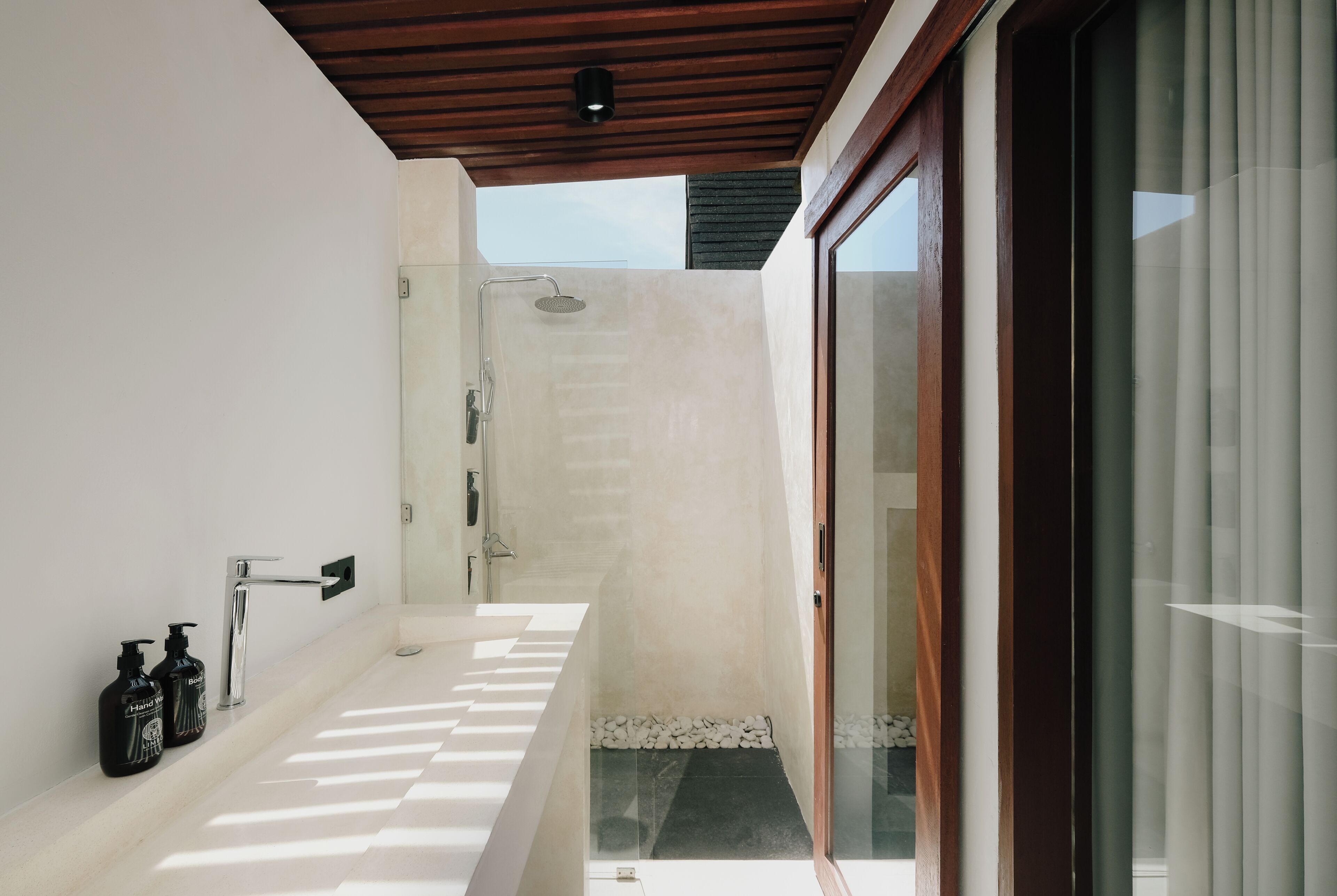 Ein modernes Badezimmer mit Dusche, Waschbecken und zwei Seifenspender.