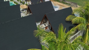 A resort with multiple bungalow-style accommodations, a swimming pool, and a view of the ocean and hills. - Limbo Lux Bungalows (Kuta)