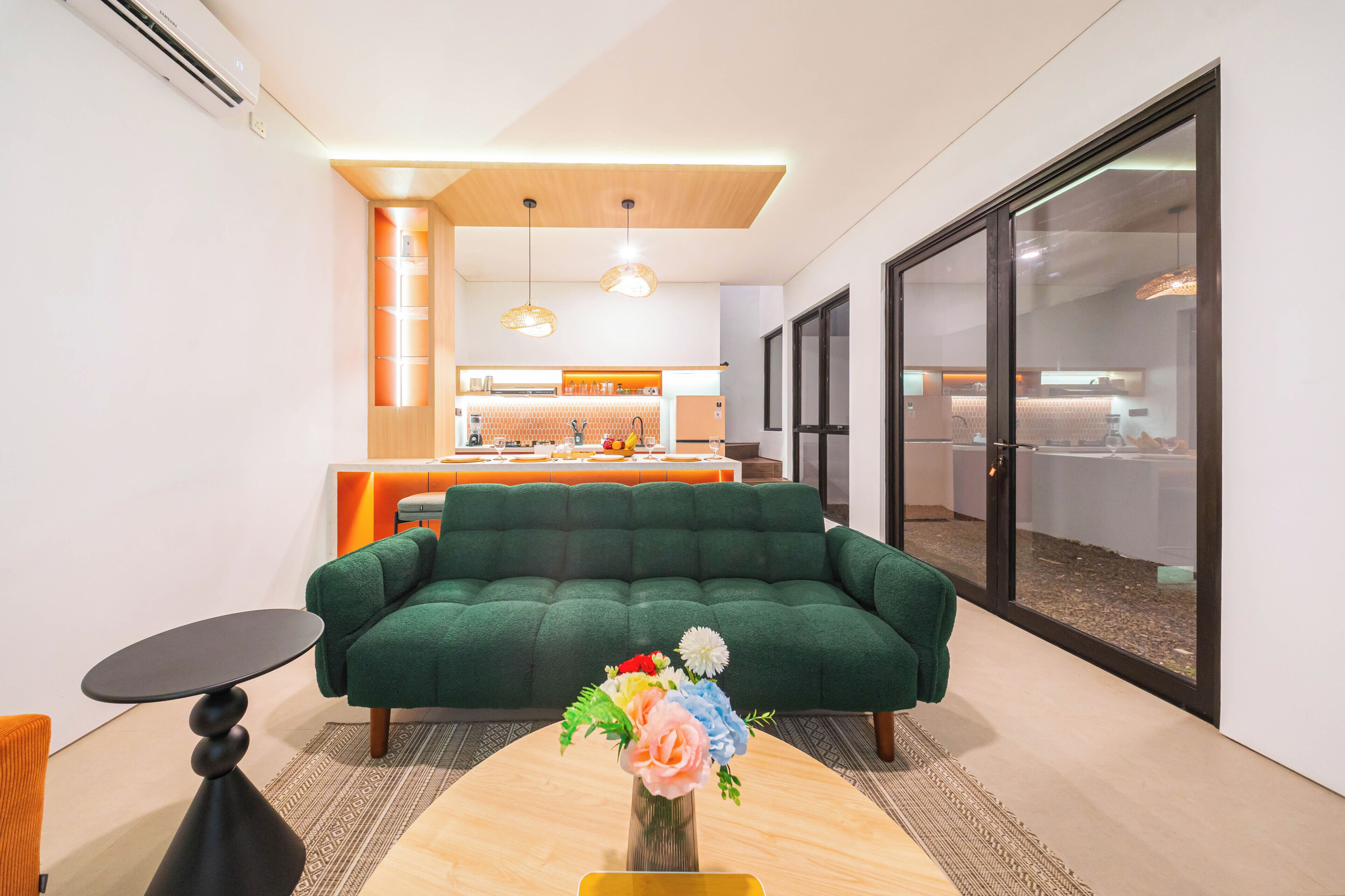 A modern living room with a green sofa, a small table, and a vase of flowers.