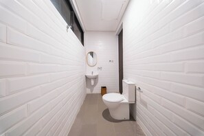 Ein schmales Badezimmer mit weißen Fliesen und einer weißen Toilette.
