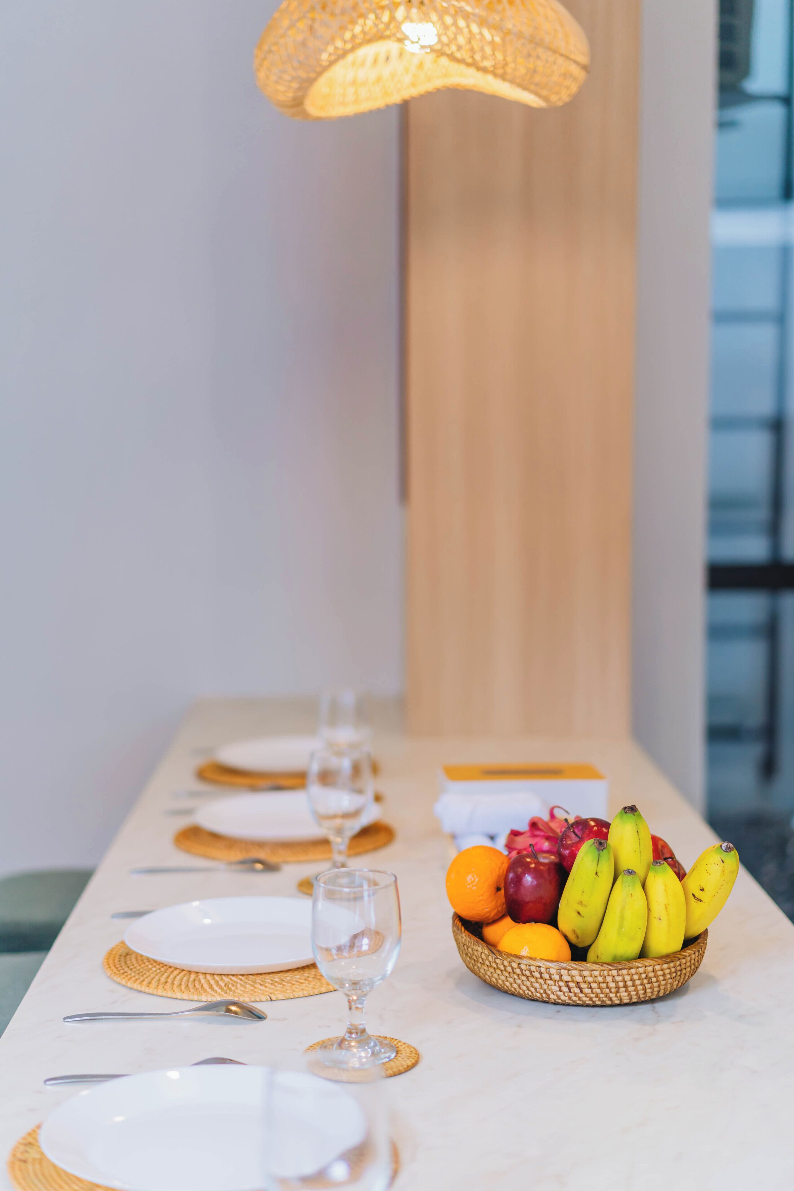 A dining table with plates, cutlery, and a fruit basket.