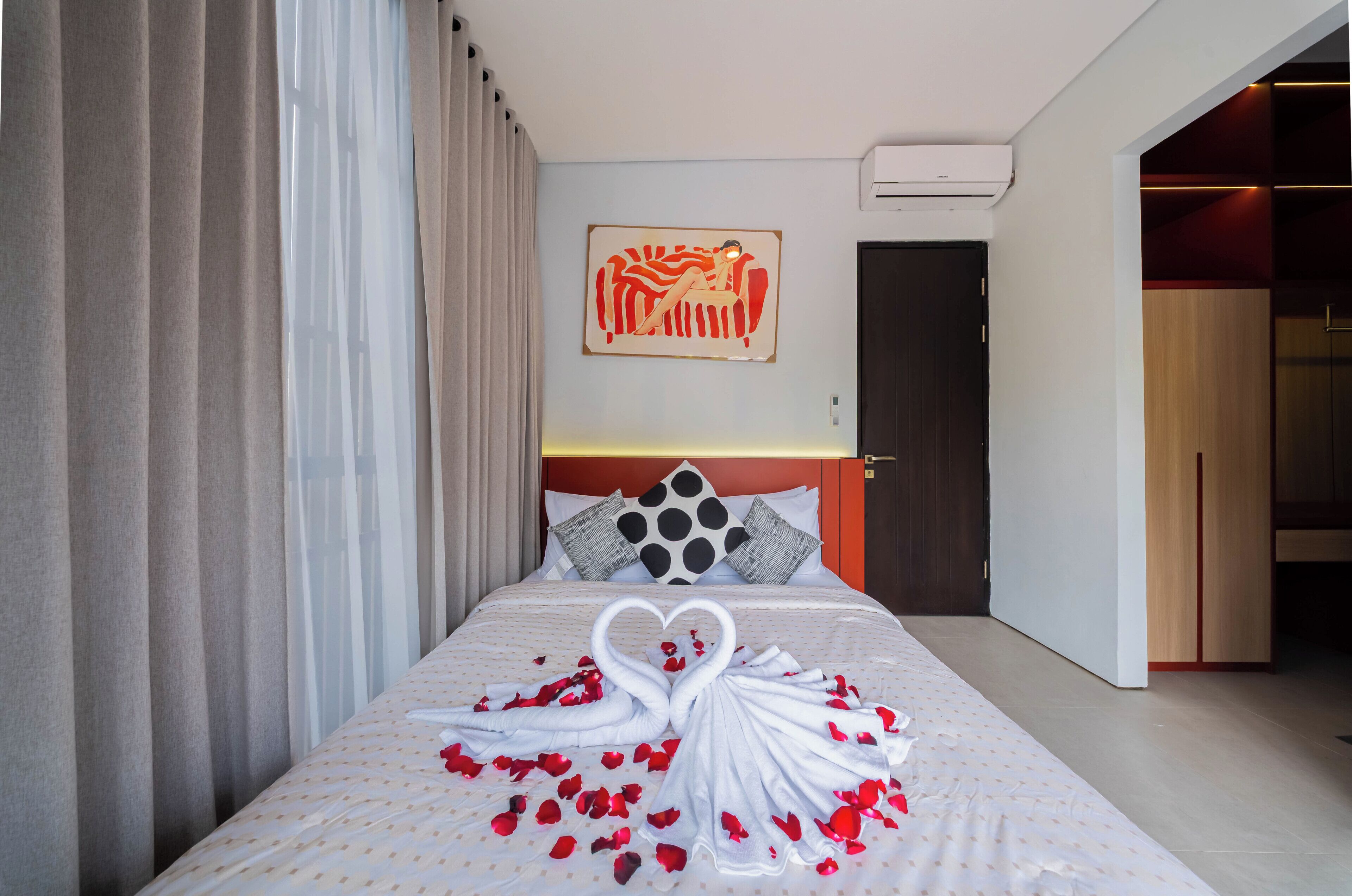 Una camera d'albergo con un letto, tende, un quadro e una porta.