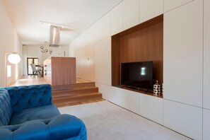 A modern living room with a blue sofa, a flat-screen TV, and a wooden accent wall. - Porto Riverviews | Monte dos Judeus (Porto)