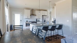 A modern kitchen with white cabinets, a central island with bar stools, and pendant lighting. - 4BR Nashville Stay w/ Pool Table & Patio! (Nashville)