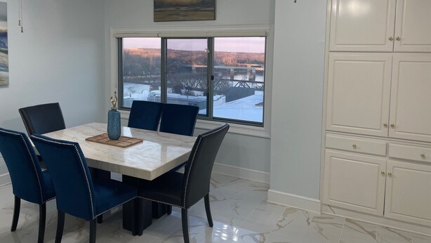 Un comedor con mesa y sillas, vista a un río y un puente, y un ventilador de techo.