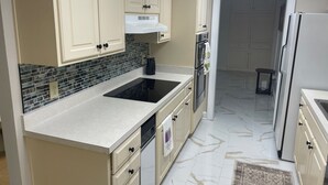 Una cocina con armarios color beige, una estufa negra y un salpicadero de azulejos.