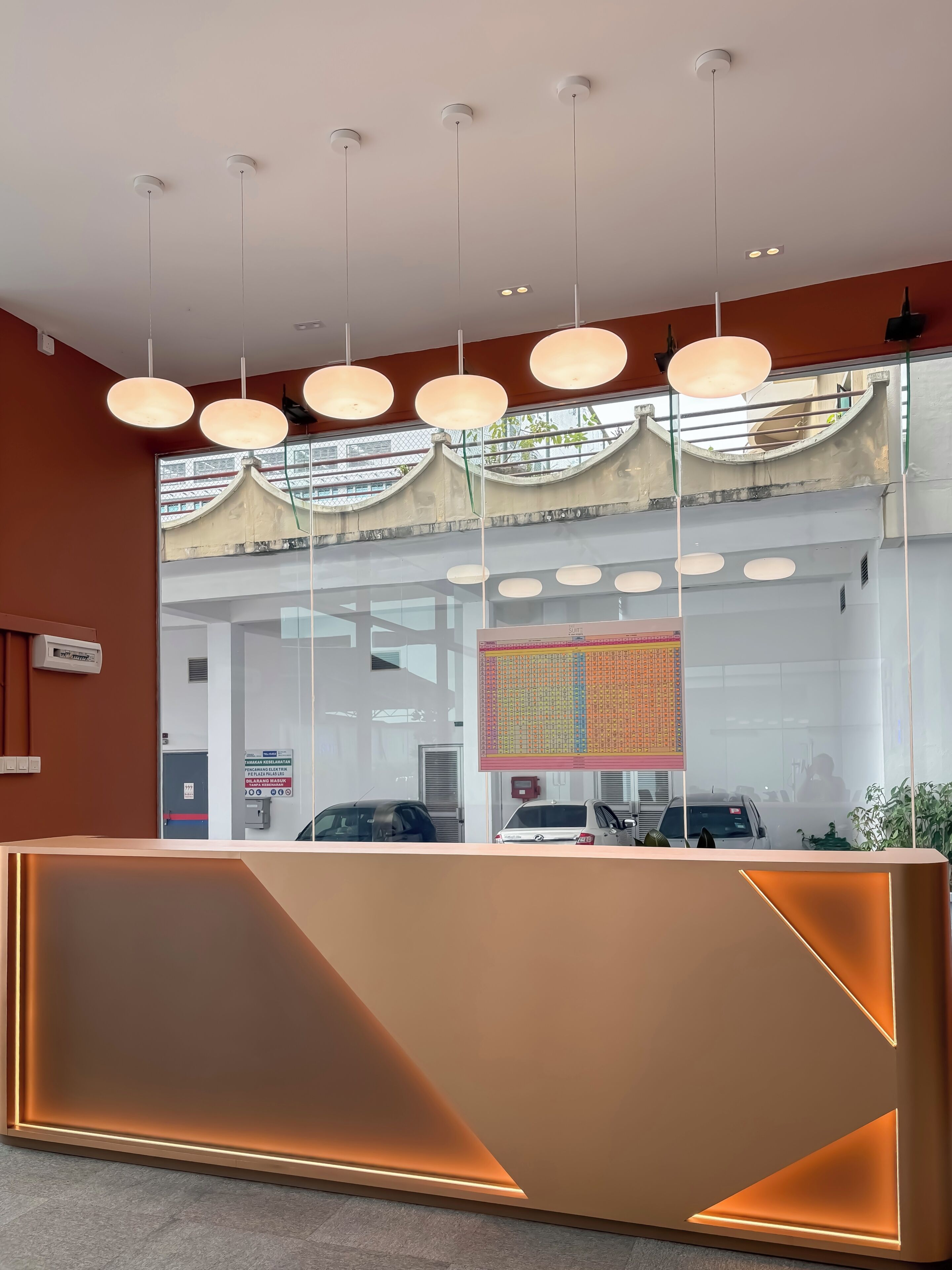 Un mostrador de recepción de diseño moderno, iluminación cenital y vistas al exterior a través de amplios ventanales.