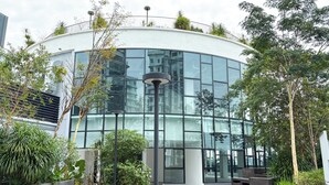 A modern building with a curved glass facade, surrounded by greenery and outdoor seating areas. - The Suite by Manhattan Group (Kuala Lumpur)
