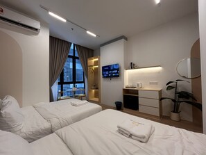 A hotel room with two beds, a desk with a flat-screen TV, a mirror, and a potted plant. - The Suite by Manhattan Group (Kuala Lumpur)