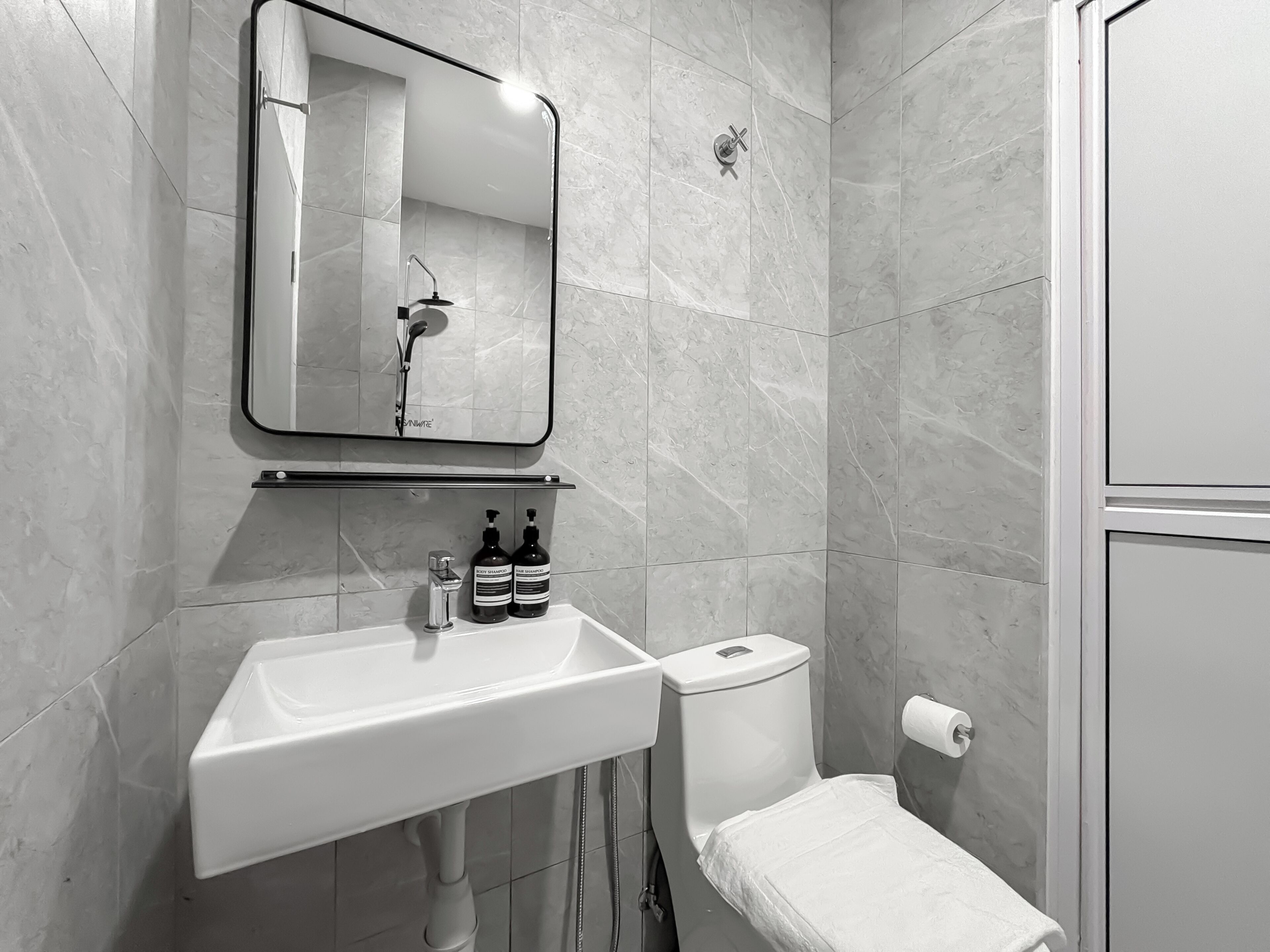 A bathroom with a white sink, mirror, and toilet.