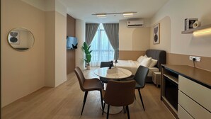 A modern hotel room with a dining area, a sofa, a TV, and a large window. - The Suite by Manhattan Group (Kuala Lumpur)