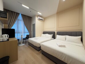 Ein Hotelzimmer mit zwei Betten, einem Schreibtisch mit Kaffeemaschine, einem Stuhl und Blick ins Freie.