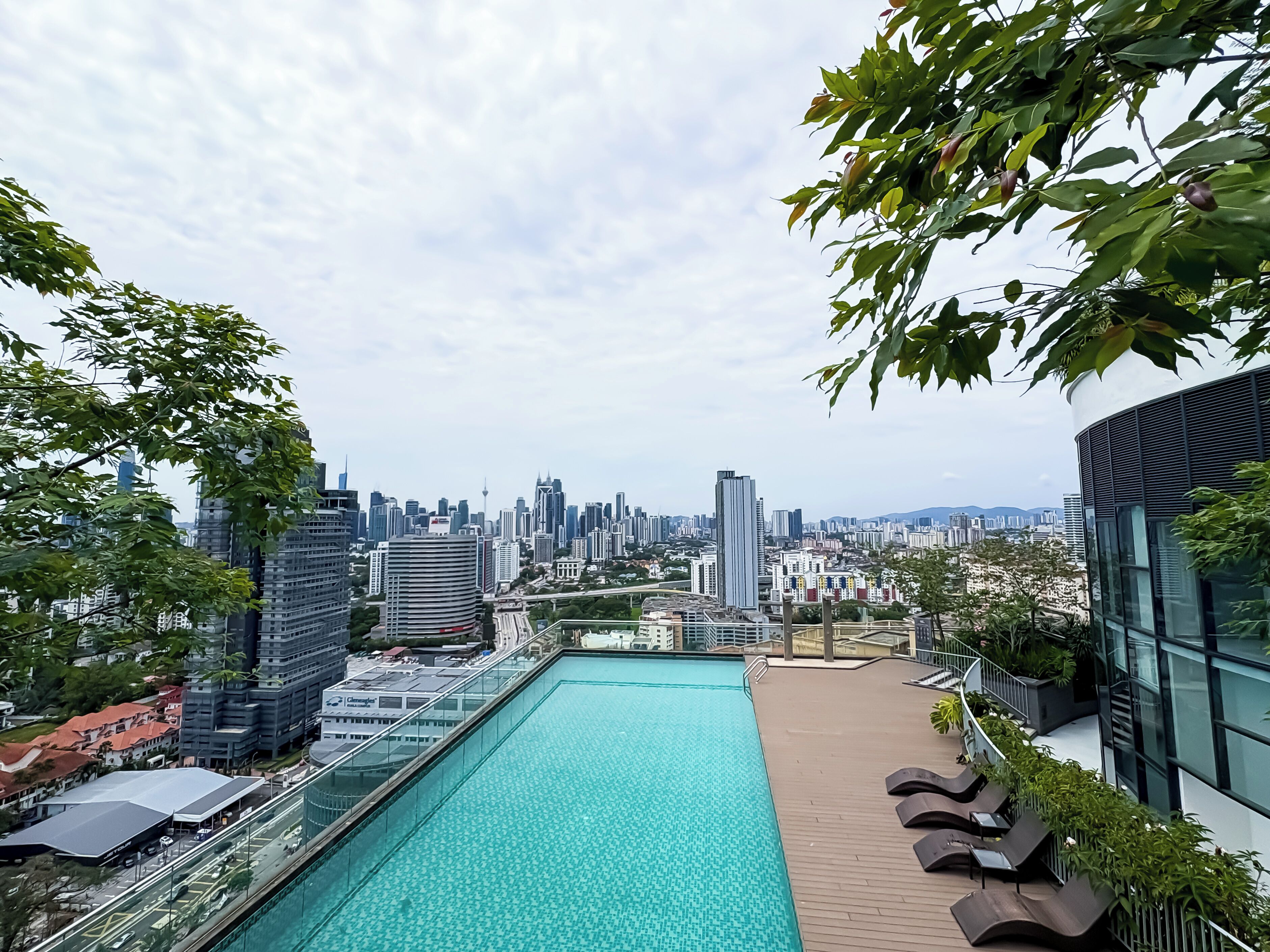 A rooftop pool with a city skyline view, lounge chairs, and modern architecture.