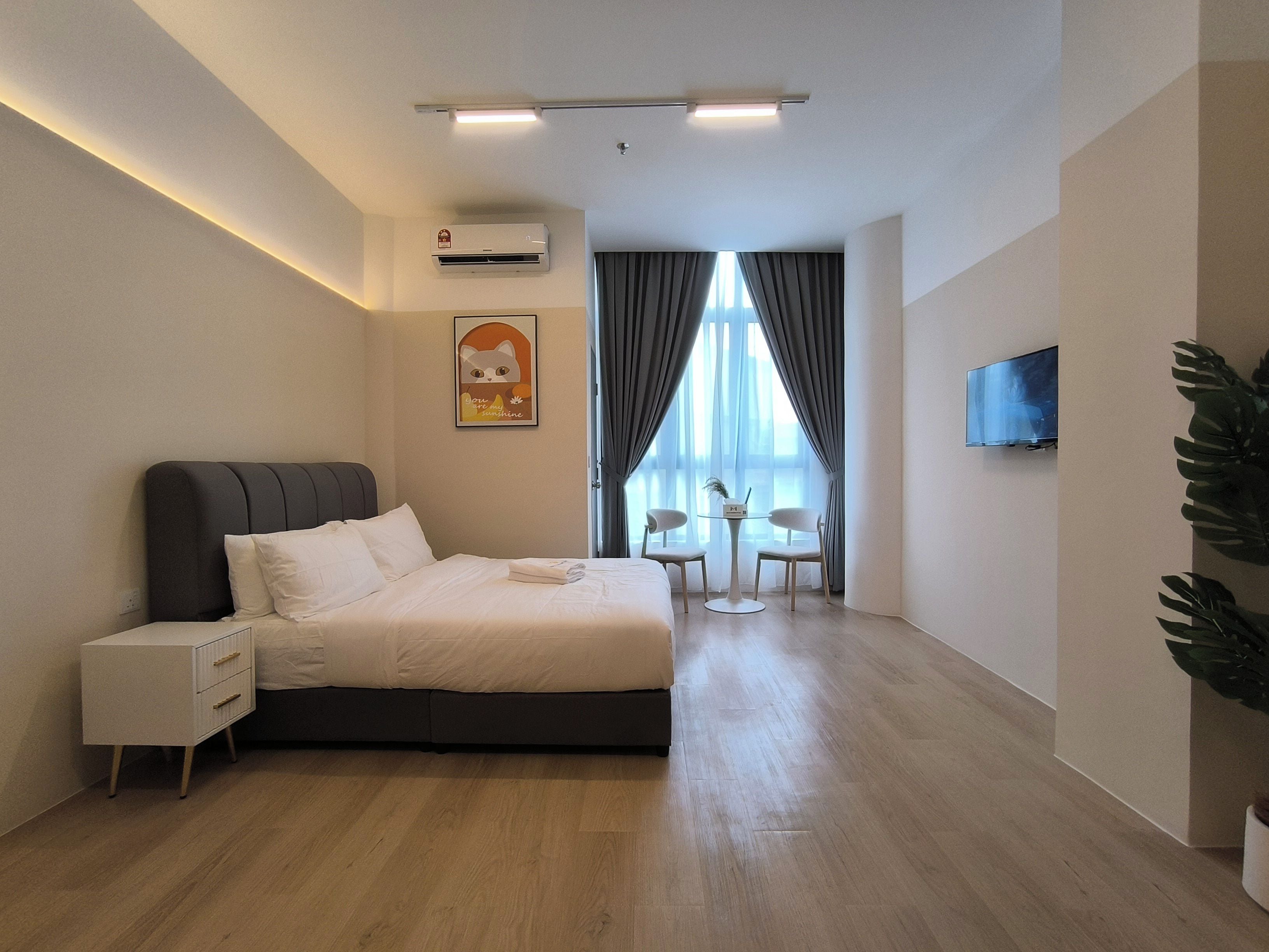 Una habitación de hotel moderna con cama, mesita de noche, aire acondicionado y un televisor montado en la pared.
