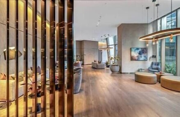 Ein modernes Interieur mit Holzboden, Sitzbereichen und großen Fenstern.