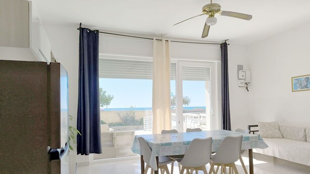 Un espace repas comprenant une table et des chaises, un ventilateur de plafond et une vue sur la mer.