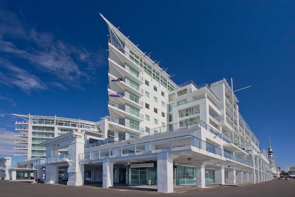 Un hotel moderno de varios pisos con una fachada blanca destacada, múltiples balcones y un cielo despejado al fondo.