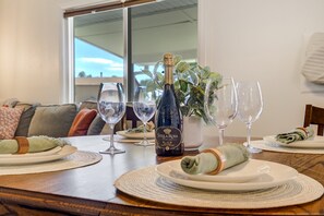 Une table à manger dressée avec des assiettes, des verres, une bouteille de vin mousseux Stella Rosa Black et une serviette enroulée.