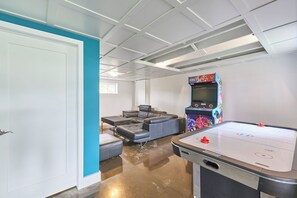 A room with a pool table, a sofa, and a video game machine.