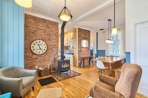 A living room with a brick wall, a clock, a fireplace, and a dining area.