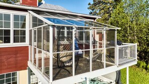 A house with a glass-enclosed porch, a chair, and a table.