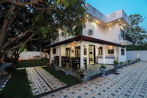 A modern two-story house with a covered patio, outdoor seating, and potted plants. - Yala Elegant Hotel (Tissamaharama)