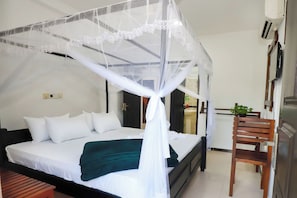 A neatly made bed with white bedding, a green throw blanket, and a white canopy. - Yala Elegant Hotel (Tissamaharama)