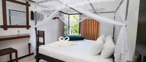 A hotel room with a bed, a desk, a chair, and a window with curtains.