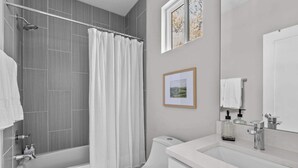 Een moderne badkamer met een bad, toilet en wastafel.