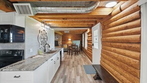 A log cabin interior with a kitchen, dining area, and a fireplace. - Sunshine Lakehouse at Canyon Lake (Canyon Lake)