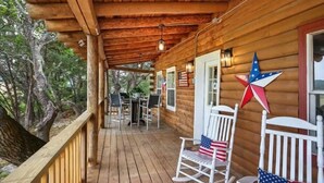 A wooden deck with a covered area, outdoor seating, and American flag decorations. - Sunshine Lakehouse at Canyon Lake (Canyon Lake)