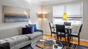 Un salon moderne avec un canapé gris, une table basse et un coin repas comprenant des chaises et une table.