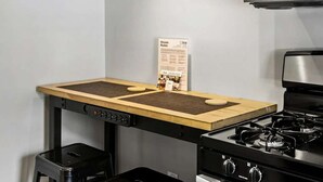 A compact kitchen with a gas stove, a microwave, and a wooden island with stools. - Brookwood Courtyard by BCA Furnished Apartments Bcc1b 03 C (Atlanta)