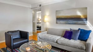 A living room with a grey sofa, black armchair, and a coffee table with decorative items. - Brookwood Courtyard by BCA Furnished Apartments Bcc1b 03 C (Atlanta)