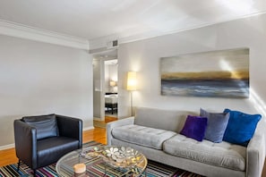 Ein Wohnzimmer mit grauem Sofa, schwarzem Sessel und einem Couchtisch mit Dekoration.