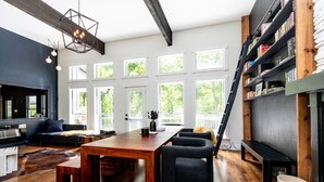 Ein modernes Wohnzimmer mit einem Holzesstisch, schwarzen Stühlen, einer Couch und einem Bücherregal.