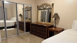 Une chambre d’hôtel avec un lit, une commode, un miroir et une porte coulissante.