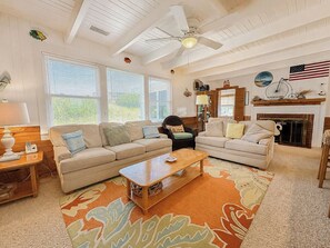 Ein Wohnzimmer mit zwei Sofas, einem Couchtisch, einem Kamin und einem Deckenventilator.