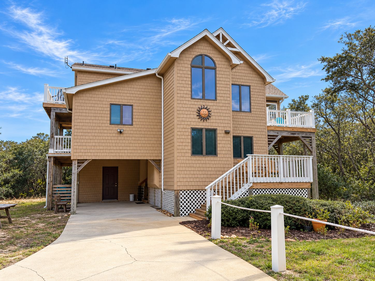 A two-story house with a covered front porch, a deck, and a small outdoor seating area.