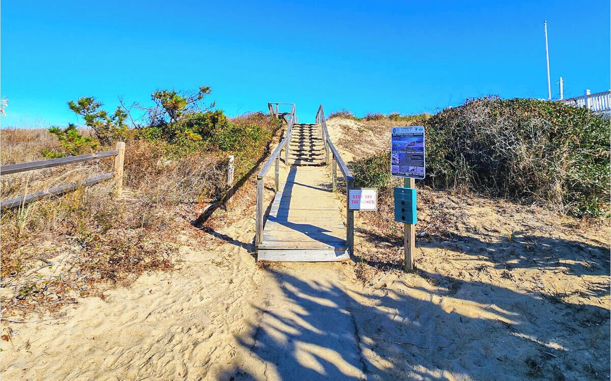 A wooden staircase leading to Hickory Trail Beach Access with a 'Keep Off The Lines' sign.