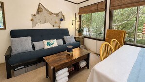 A room with a sofa, a wooden coffee table, a bed, and a chair. - Sea Gables -  Oceanside 3 BR home on Private Wooded Lot (Southern Shores)