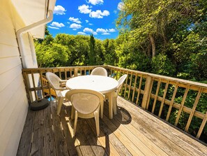 Eine Holzterrasse mit rundem Tisch und Stühlen, umgeben von einem Holzgeländer.
