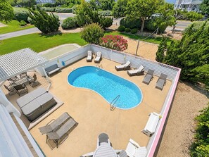 Una piscina con sillones de descanso y una zona de estar cubierta.
