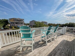 A wooden deck with chairs and a railing. - Salty Paws - 4 BR Oceanside vacation home in the heart of Duck w/Private Pool (Duck)