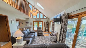 A spacious living area with a sofa, a chair, a lamp, and a view of the outdoors. - Salty Paws - 4 BR Oceanside vacation home in the heart of Duck w/Private Pool (Duck)
