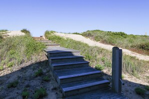 Eine Holztreppe, die einen sandigen Hang hinaufführt.