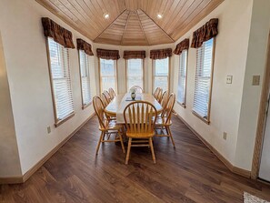 A dining room with a wooden table and chairs, large windows with blinds, and a wooden ceiling. - Twinscape - 5 BR Oceanfront Escape w/Community Pool/Tennis (Duck)