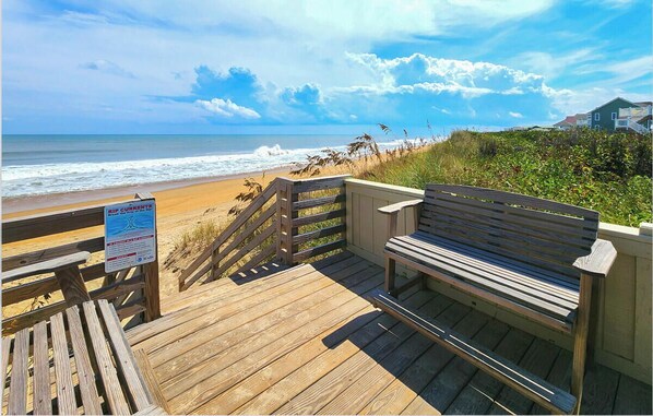 A wooden boardwalk leading to a beach with a bench and a sign about rip currents. - Twinscape - 5 BR Oceanfront Escape w/Community Pool/Tennis (Duck)