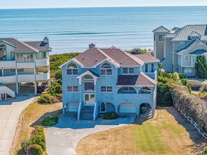 A multi-story house with a central entrance, two garages, and a view of the ocean. - Twinscape - 5 BR Oceanfront Escape w/Community Pool/Tennis (Duck)