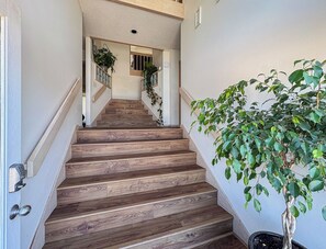 A wooden staircase with a potted plant on the right. - Twinscape - 5 BR Oceanfront Escape w/Community Pool/Tennis (Duck)